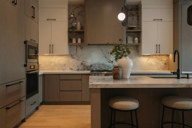 A modern kitchen lit by a globe pendant light over the island and warm strip lights under the overhead cupboards.