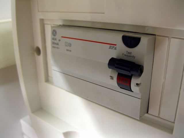 A white safety switch (RCD) in a home switchboard, with a black test button marked Test Frequently and its red ON flag showing.